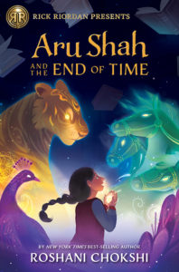 Cover of Aru Shah and the End of Time by Roshani Chokshi. A girl with a long braid, wearing Spider-Man pajamas, looks up at a ghostly tiger, horses, and peacock while books swirl down in her direction.
